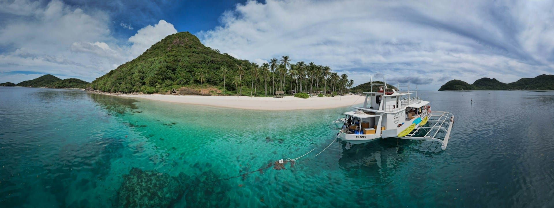 A dive boat moored off a white-sand beach