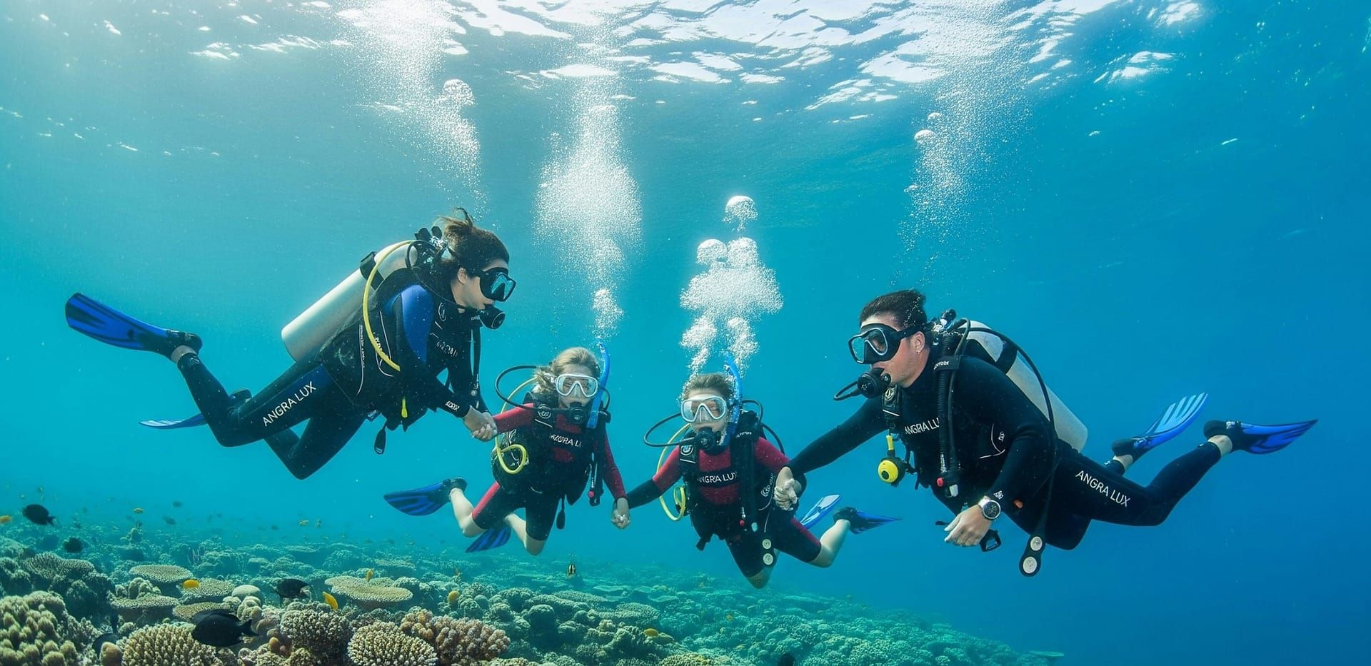 Four divers holding hands above the reef